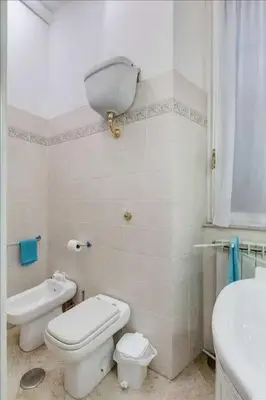 a white bathroom with a toilet and a sink at Holiday Jeans Apartment in Rome