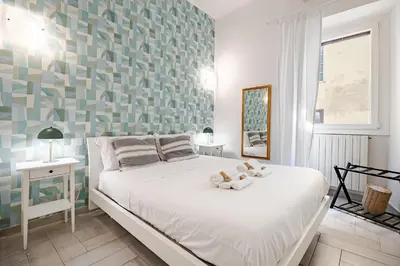 a bedroom with a white bed with a green wall at TrastEva nel cuore di Trastevere a San Cosimato in Rome