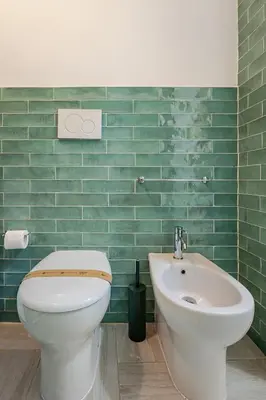 a green tiled bathroom with a toilet and a sink at TrastEva nel cuore di Trastevere a San Cosimato in Rome