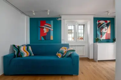 a blue couch in a room with paintings on the wall at Tiburtina Station Rooftop Angel Joy with Private Terrace - Superattico con Terrazzo privato in Rome