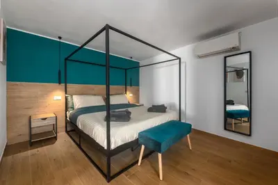 a bedroom with a canopy bed and a blue chair at Tiburtina Station Rooftop Angel Joy with Private Terrace - Superattico con Terrazzo privato in Rome