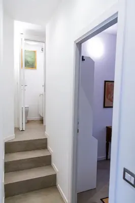 a hallway with stairs in a house with white walls at Habemus Casam in Rome