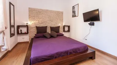 a bedroom with a purple bed with a brick wall at Ostilia Loft in Rome