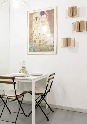 a white table with two chairs and a painting on a wall at RHOMENJOY Pied-à-terre Colosseo in Rome