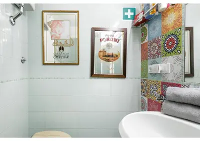 a bathroom with a toilet and some pictures on the wall at RHOMENJOY Pied-à-terre Colosseo in Rome