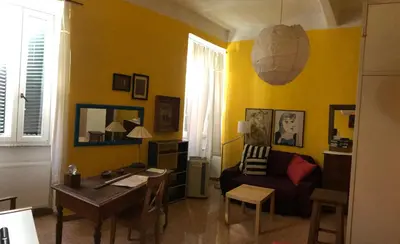 a yellow living room with a desk and a chair at Appartamento del Boschetto in Rome