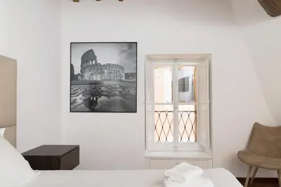 a bedroom with a bed and a window and a chair at Appartamento Campo Marzio Lusso in Rome