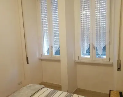 a bedroom with two windows with white blinds at Hanna's House Metro Pyramid in Rome