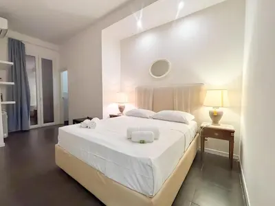 a white bedroom with a large bed with white sheets at Beautiful apartment within walking distance of the Vatican in Rome