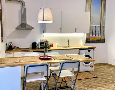 a kitchen with white cabinets and a table with chairs at Karma Trastevere Loft in Rome