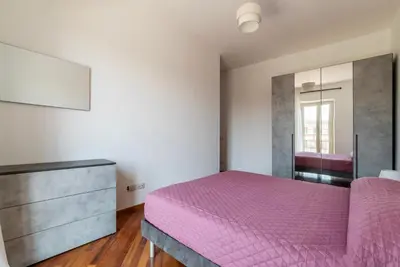 a bedroom with a pink bed and a dresser at GuestHost - Bright Apartment in Metro San Giovanni in Rome
