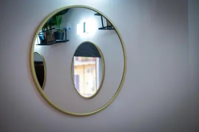 a round mirror on a wall with two shelves at ht vittorio in Rome