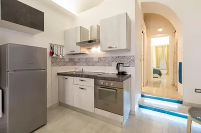 a kitchen with white cabinets and a sink and a refrigerator at lollo's home in Rome