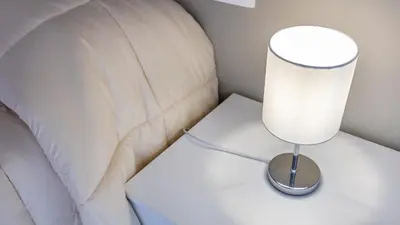 a white lamp on a table next to a bed at Rosina's House in Rome