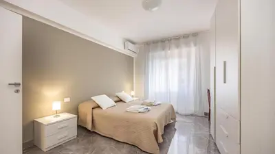 a white bedroom with a bed and a window at Rosina's House in Rome