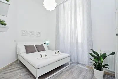 a white room with a bed and a potted plant at DaliTourism - Colosseo Experience 28 in Rome