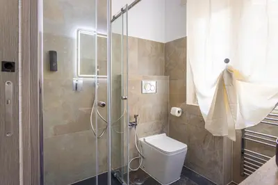a bathroom with a toilet and a glass shower at Aurelia Garden Suite in Rome