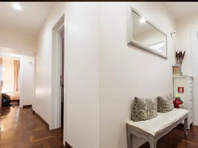 a white hallway with a bench and a mirror at La Piccola Maison in Rome