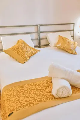 two beds with gold and white pillows and a towel at Casa Pan in Rome