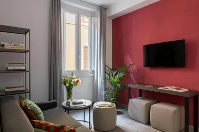 a living room with a couch and a red wall at Now Apartments, ApartHotel in the heart of Rome in Rome