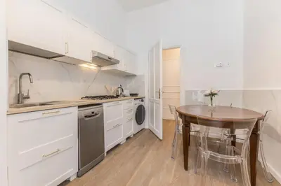 a kitchen with white cabinets and a table and a sink at Elegant 3-bedroom apartment near the Metro in Rome