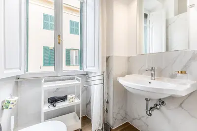 a white bathroom with a sink and a mirror at Elegant 3-bedroom apartment near the Metro in Rome