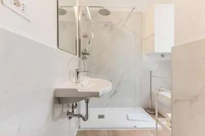 a white bathroom with a sink and a mirror at Elegant 3-bedroom apartment near the Metro in Rome