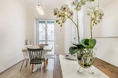 a dining room with a table and a vase with flowers at Elegant and spacious apartment facing the subway near the Vatican in Rome