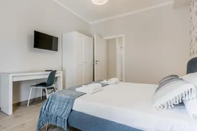 a white bedroom with a bed and a desk at Elegant and spacious apartment facing the subway near the Vatican in Rome