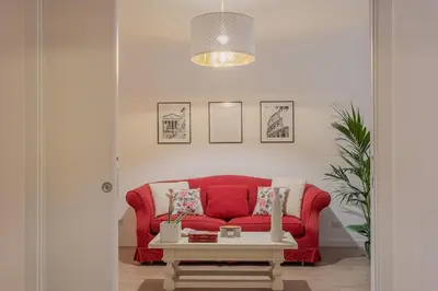 a red couch in a living room with a table at MyRentalInn - Vatican Prestigious Apartment in Rome