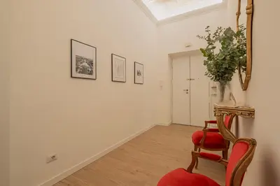 a room with a red chair and a vase of flowers at MyRentalInn - Vatican Prestigious Apartment in Rome