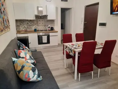 a living room and kitchen with a table and red chairs at Home Delfini in Trastevere in Rome