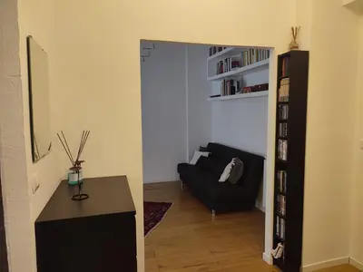 a living room with a black couch and a book shelf at Tanner's Apartment - Piramide in Rome