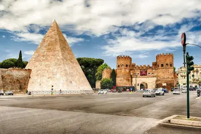 a building with a pyramid and cars in a street at Tanner's Apartment - Piramide in Rome