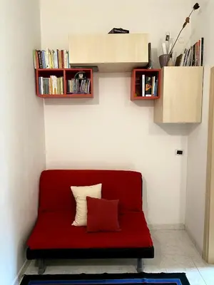 a red couch sitting in a room with books at Small and very small house in Rome