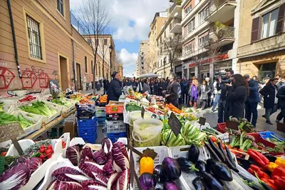 a group of people standing around a market with vegetables at Small and very small house in Rome