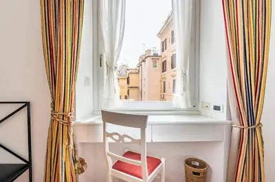 a chair sitting in front of a window with curtains at Fori Imperiali Colosseum in Rome