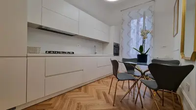 a kitchen with white cabinets and a table and chairs at Beautiful Apartment San Pietro in Rome