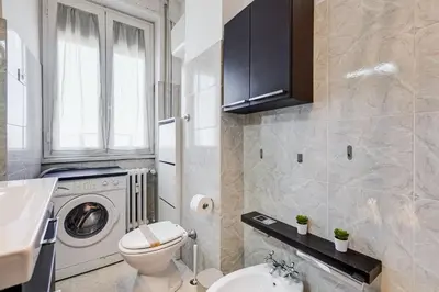 a bathroom with a toilet and a washer and dryer at L'oasi romana di Daniela in Rome