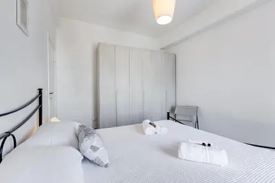 a white bedroom with two towels on a bed at L'oasi romana di Daniela in Rome