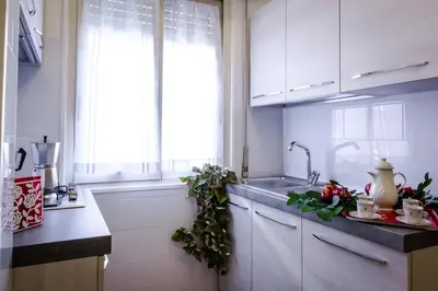 a kitchen with white cabinets and a sink and a window at Apartment in the center of Rome with spectacular view of the Dome in Rome
