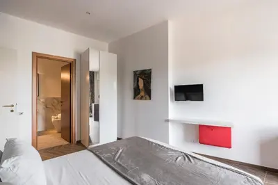 a white bedroom with a bed and a tv on the wall at 59 Riverside in Rome