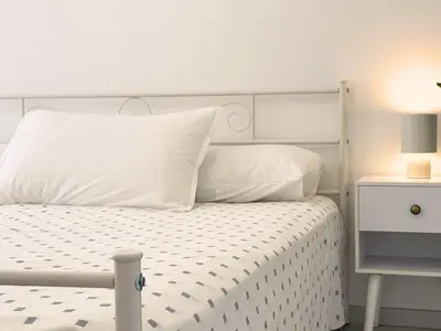 a white bed with white pillows and a night stand at Trastevere Home in Rome