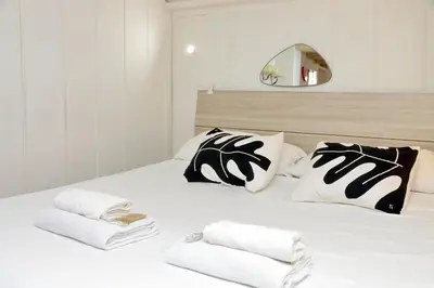 a white bed with black and white pillows and a mirror at Al moro in Rome