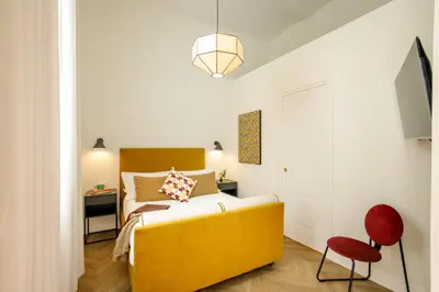 a bedroom with a yellow bed and a red chair at Daplace - Serenella Apartment in Rome