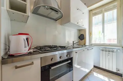 a white kitchen with a stove and a sink at Domus Romana Trieste in Rome