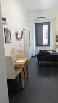 a room with a desk and a bed and a table and chairs at little roma apartment in Rome