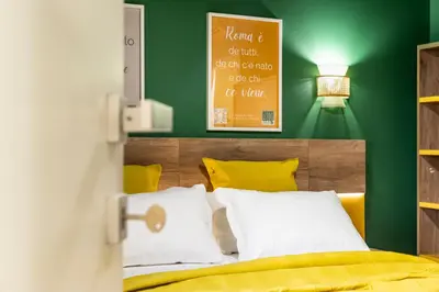 a bedroom with green walls and a bed with yellow pillows at Notte Ai Colli - Rooms & Kitchen in Rome