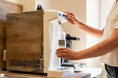 a man is putting a bottle into a machine at Notte Ai Colli - Rooms & Kitchen in Rome