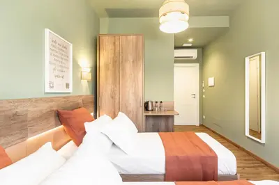a hotel room with two beds and a table at Notte Ai Colli - Rooms & Kitchen in Rome